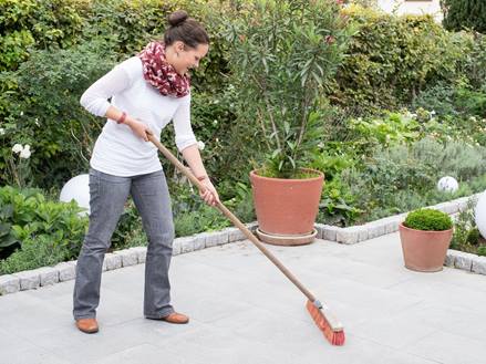 Frau reinigt Granit Mundo Grau-Terrasse