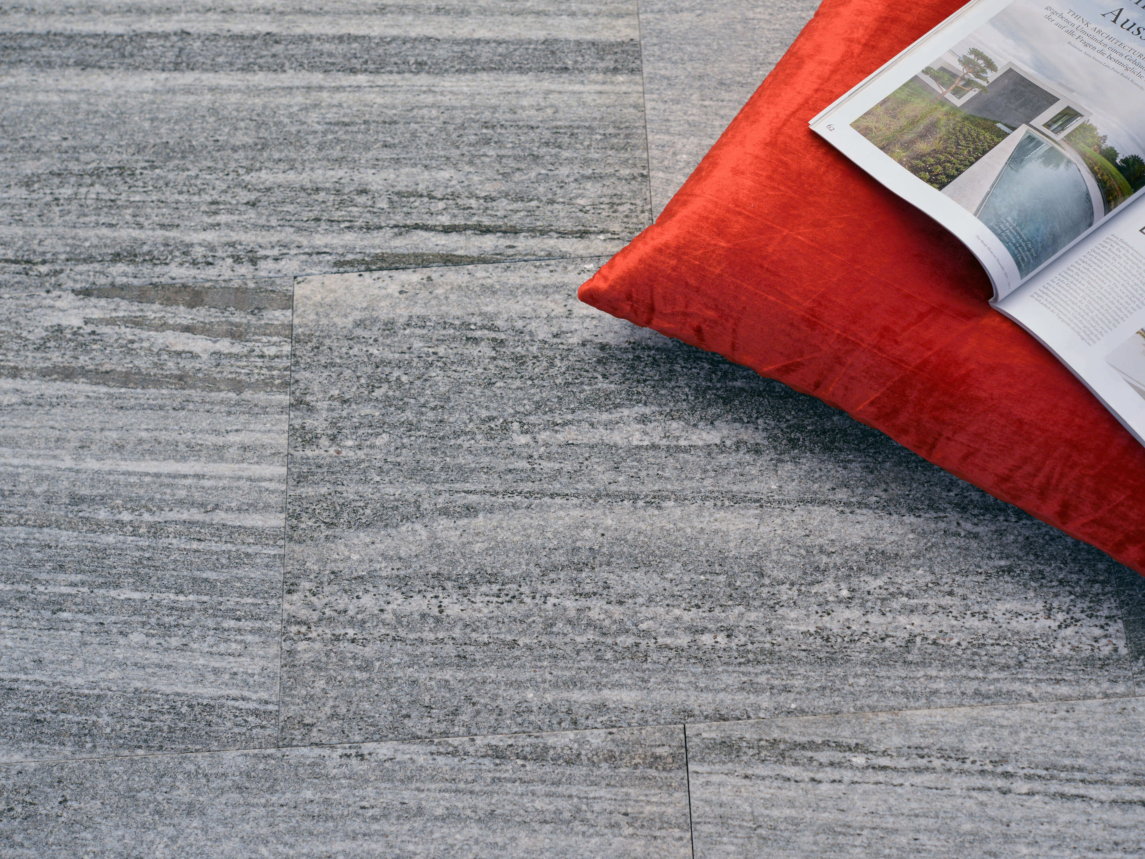 Gneisplatten Urban Grey Line mit orangefarbenem Kissen und Zeitschrift