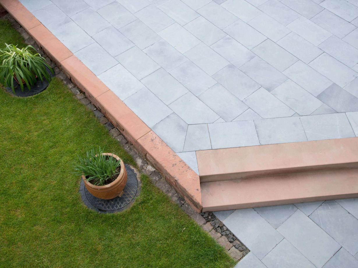 Blaustein Azur harmoniert mit vielen Farben. Terrasse aus Kalkstein mit Gras und Pflanzen