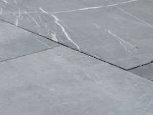 Der Used-Look macht den Blaustein einzigartig. Platten aus Kalkstein Blaustein Azur in der Nahaufnahme, in dem hellen Grauton des Natursteins sind weiße Maserungen sichtbar