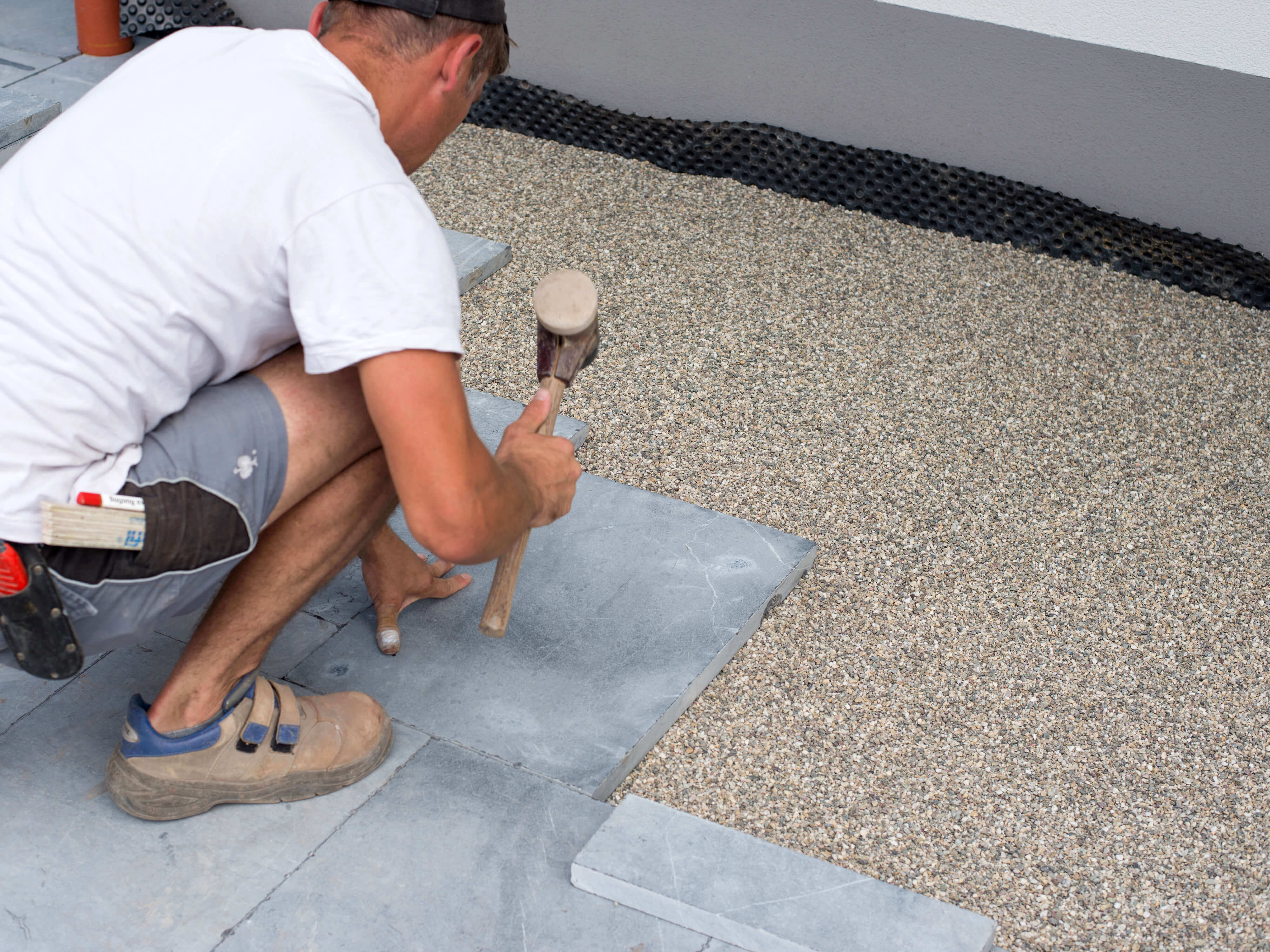 Mann verlegt Blausteinplatten im Edelsplittbett