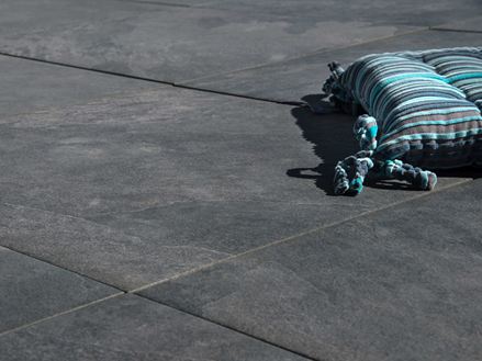 Kissen liegt auf dunkelgrauen Feinsteinzeug-Platten Alpine Black