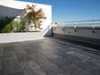 Terrasse mit schwarzem Schiefer als Bodenbelag und weisser Wand im Hintergrund