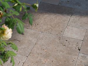 Die Spätnachmittagssonne spielt auf dem Terrassenboden, von rechts ragen Zweige ins Bild