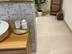 Badezimmer mit Holzelementen und Dekopflanze, Fliesen in Kalksteinoptik Sevilla Cream als Bodenbelag