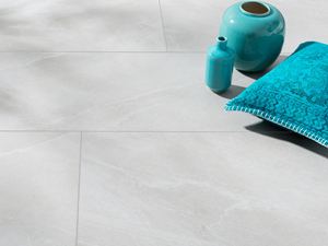 Feinsteinzeug-Fliesen in hellgrauer Schieferoptik mit türkiser Vase und türkisem Kissen