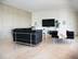 Modernes Wohnzimmer mit schwarzen Couchmöbeln und hellbeigen Travertinfliesen Classic Light als Bodenbelag