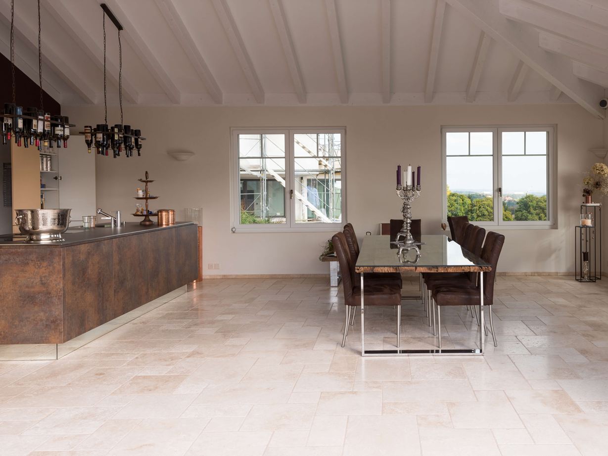 Moderne Küche trifft auf mediterranen Boden. Travertinfliesen Light im Römischen Verband in einer modernen Küche mit Esstisch und Kochinsel