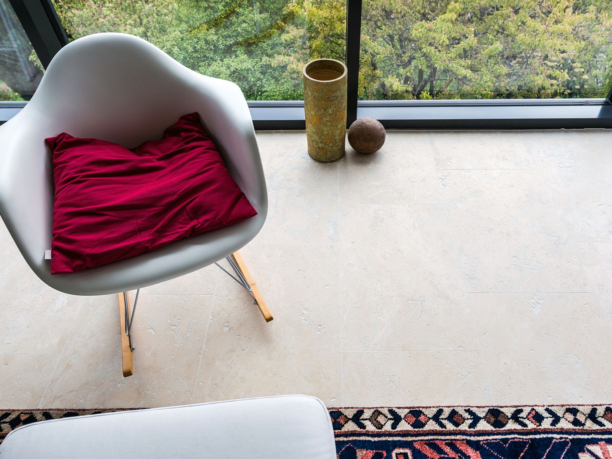 Dank gesägter Kanten sind enge Fugen möglich. Flur mit Natursteinwand, Sideboard aus Holz und beiger Travertinfliese Medium Line als Bodenbelag