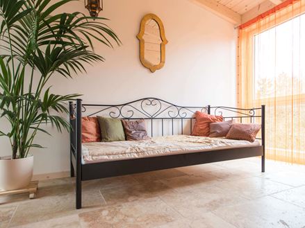 Schlafzimmer mit Bett, Pflanze und Travertin Rustic auf dem Boden