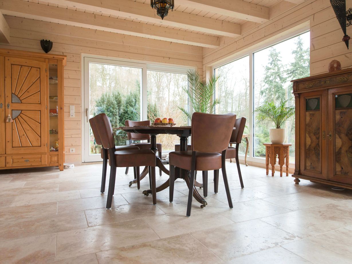 Harmonisch: der sanfte Beigeton des Travertins Essbereich mit Holzmöbeln und Travertin Rustic als Bodenbelag