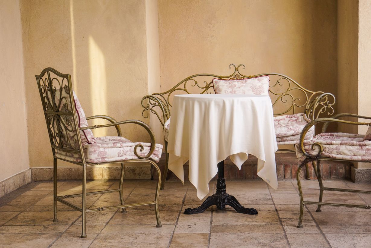 Elegante Sitzmöbel im französischen Stil mit hellem Natursteinboden