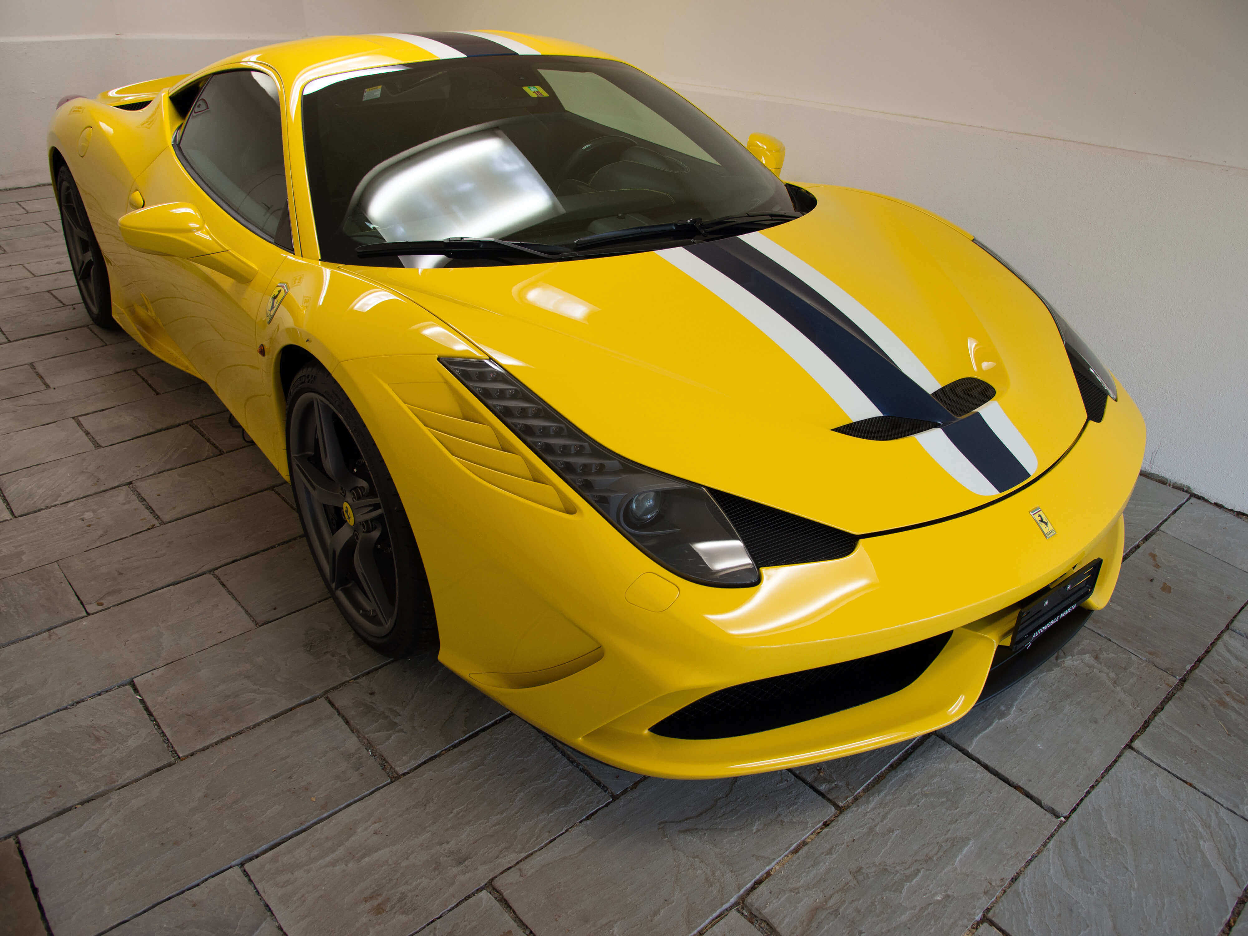 Ein gelber Sportwagen steht auf Sandsteinplatten in modernem Grau