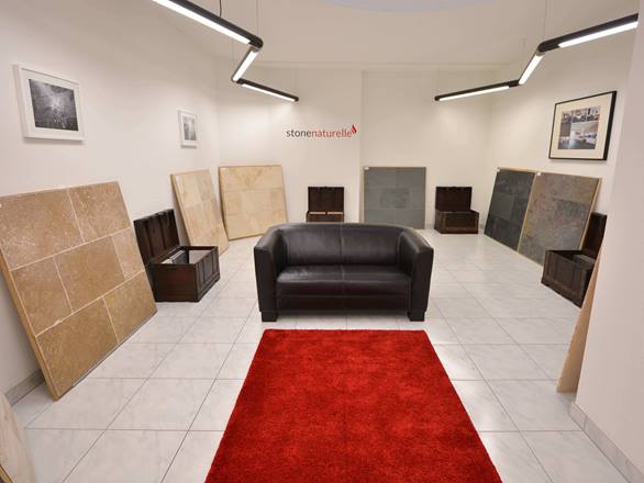 Showroom in Basel mit rotem Teppich, schwarzer Couch und mehreren Tafeln mit Steinmustern an den Wänden