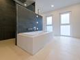 Badewanne mit Wandverkleidung aus Schiefer im Hintergrund und gebuersteter Kalksteinfliese auf dem Boden