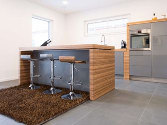 Küche mit freier Bartheke, modernen Holzelementen und dunklem Schiefer als Bodenbelag