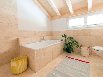 Bad mit vollverkleideter Badewanne und Travertinfliese Light als Bodenbelag