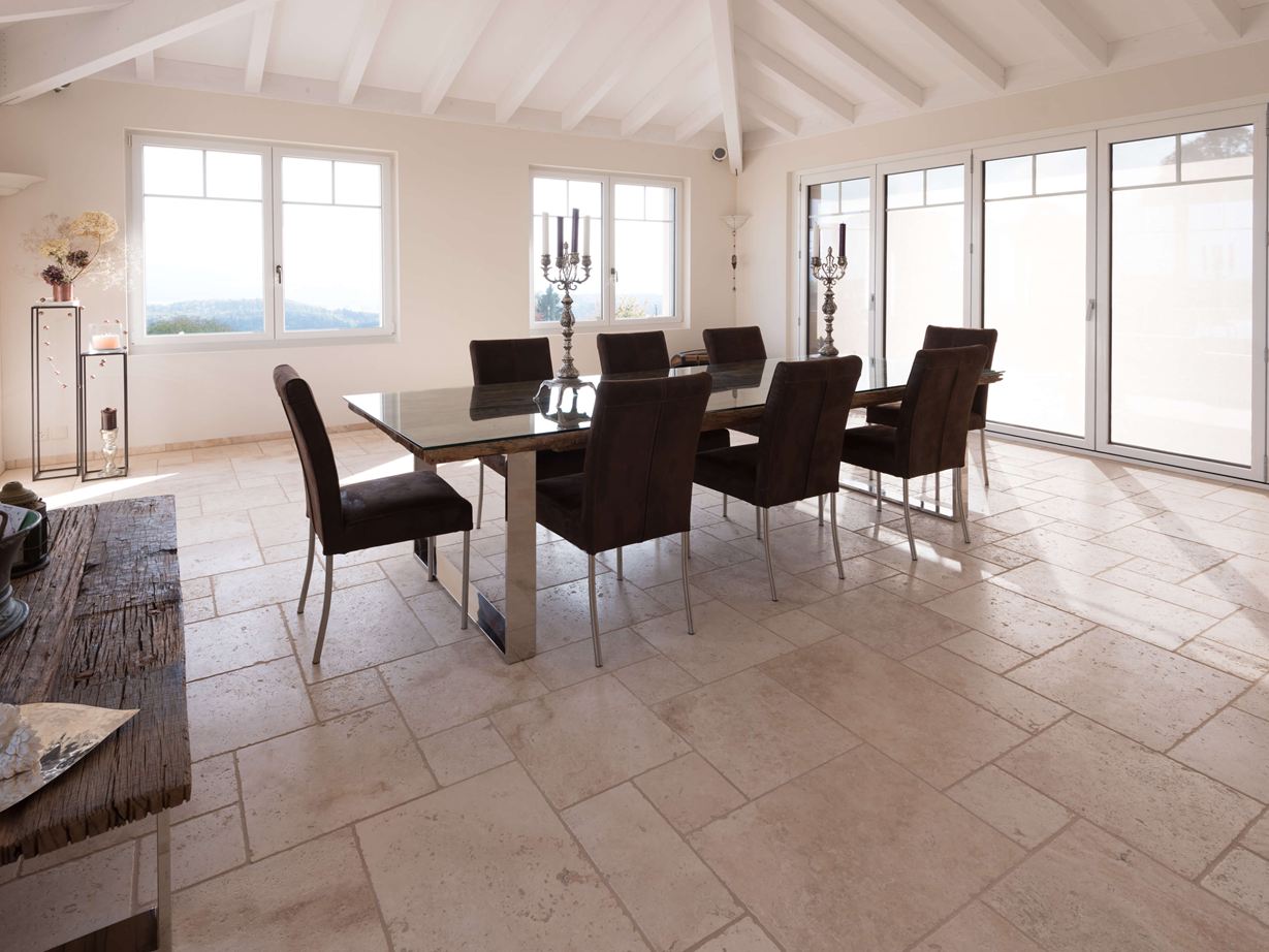Esszimmer mit hoher Decke, Tisch und Stühlen auf Travertin Light in römischem Verband