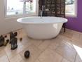 Freistehende Badewanne mit orientalischen Accessoires auf Travertinfliese Light mit getrommelter Oberfläche