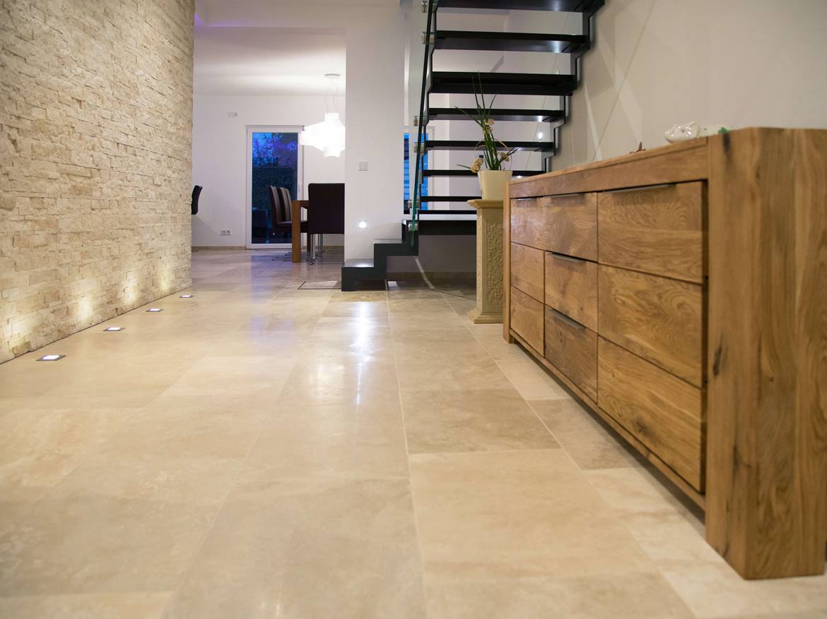 Flur mit Natursteinwand, Sideboard aus Holz und beiger Travertinfliese Medium Line als Bodenbelag