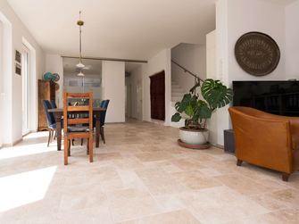 Wohnzimmer mit Holzmöbeln, weissen Wänden und Travertinfliese Medium als Bodenbelag