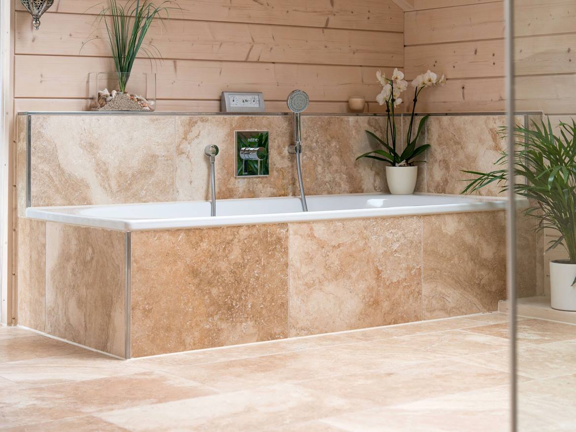 Badewanne mit Travertinfliese Rustic verkleidet und Holzwand im Hintergrund