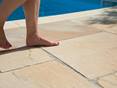 Füsse auf Sandstein Platten am Poolrand