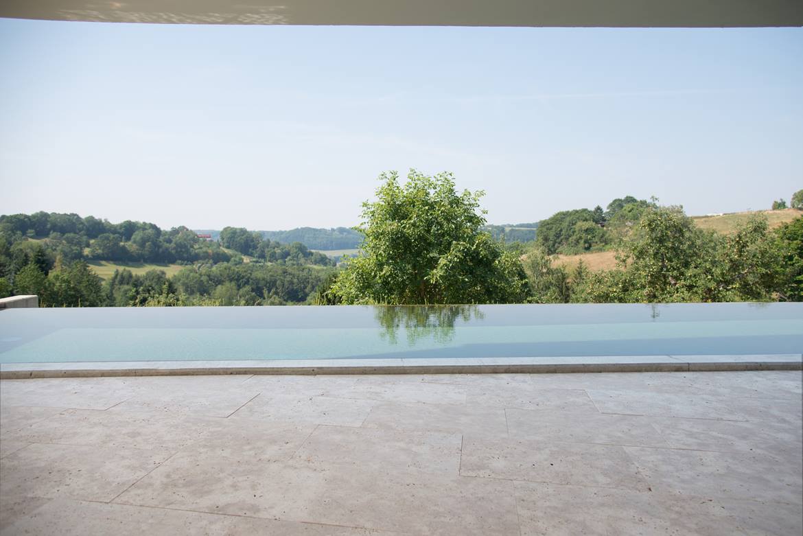 Pool mit Garten im Hintergrund und Travertinplatten als Bodenbelag