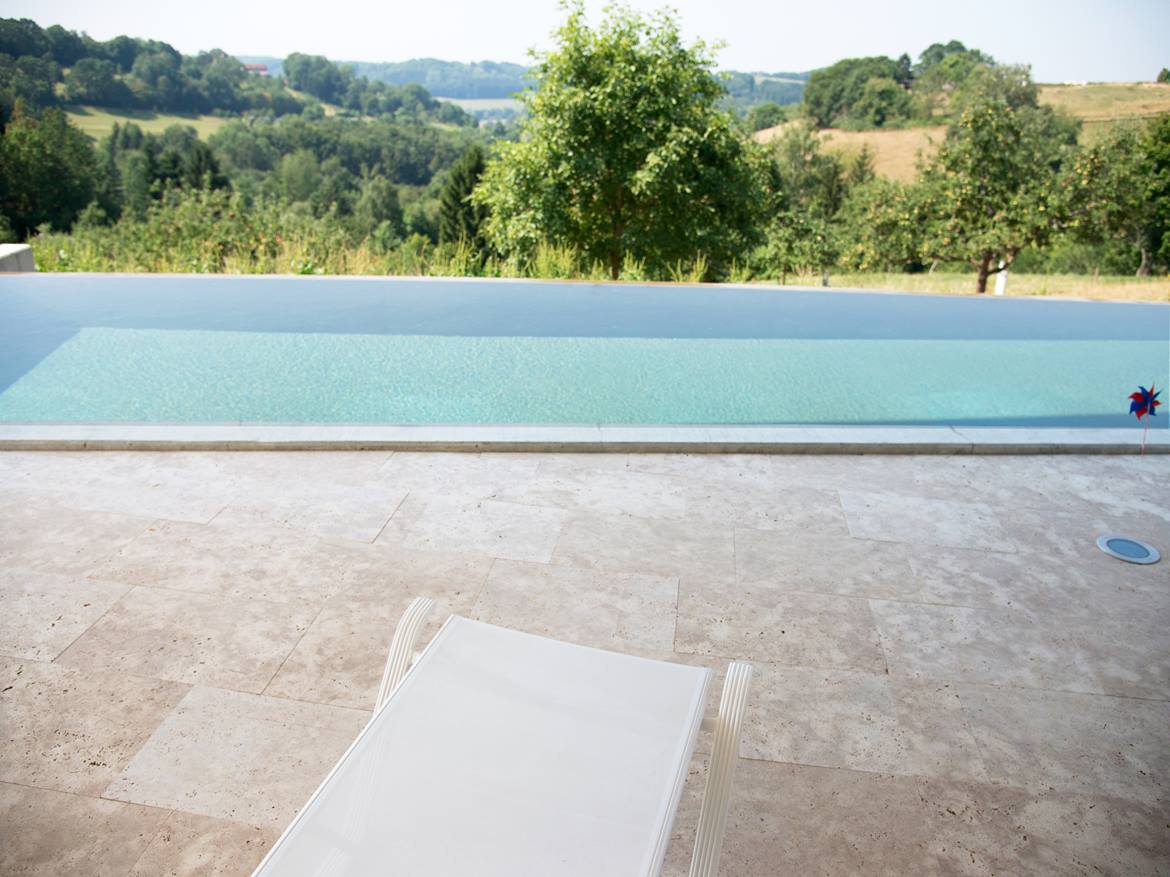 Pool umrandet mit Travertinplatte Medium Line, im Hintergrund Natur