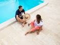 Mann und Frau sitzen am Pool, Bodenbelag Travertin Terrassenplatten