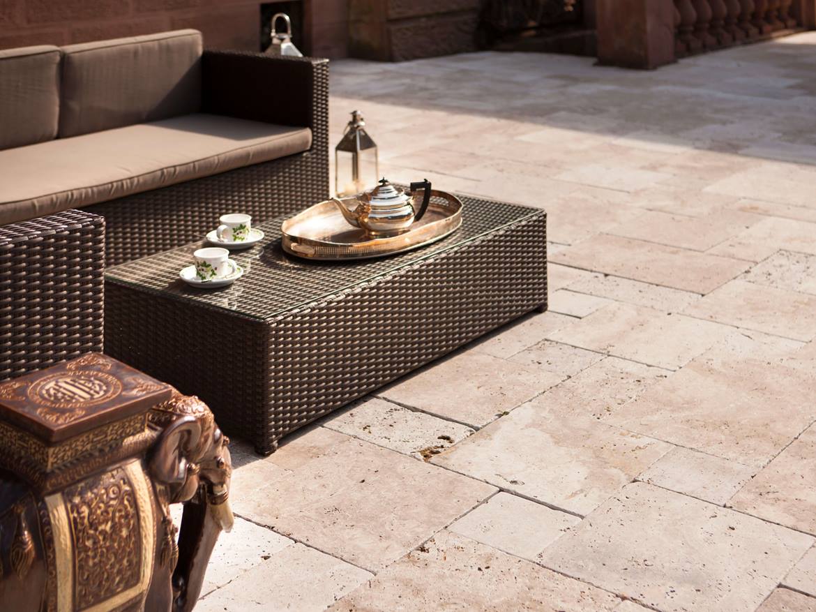 Gartensofa mit gedecktem Teetisch und bronzenem Elefantenaccessoires auf getrommelter Travertinplatte Medium