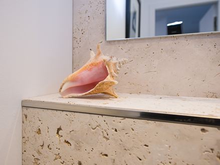 Travertin-Wandfliesen mit Muscheldeko im Bad