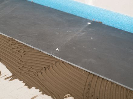 Fugenkreuze als Abstandshalter zwischen zwei Schieferfliesen