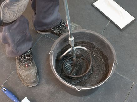 Fugenmörtel wird in einem Eimer angerührt