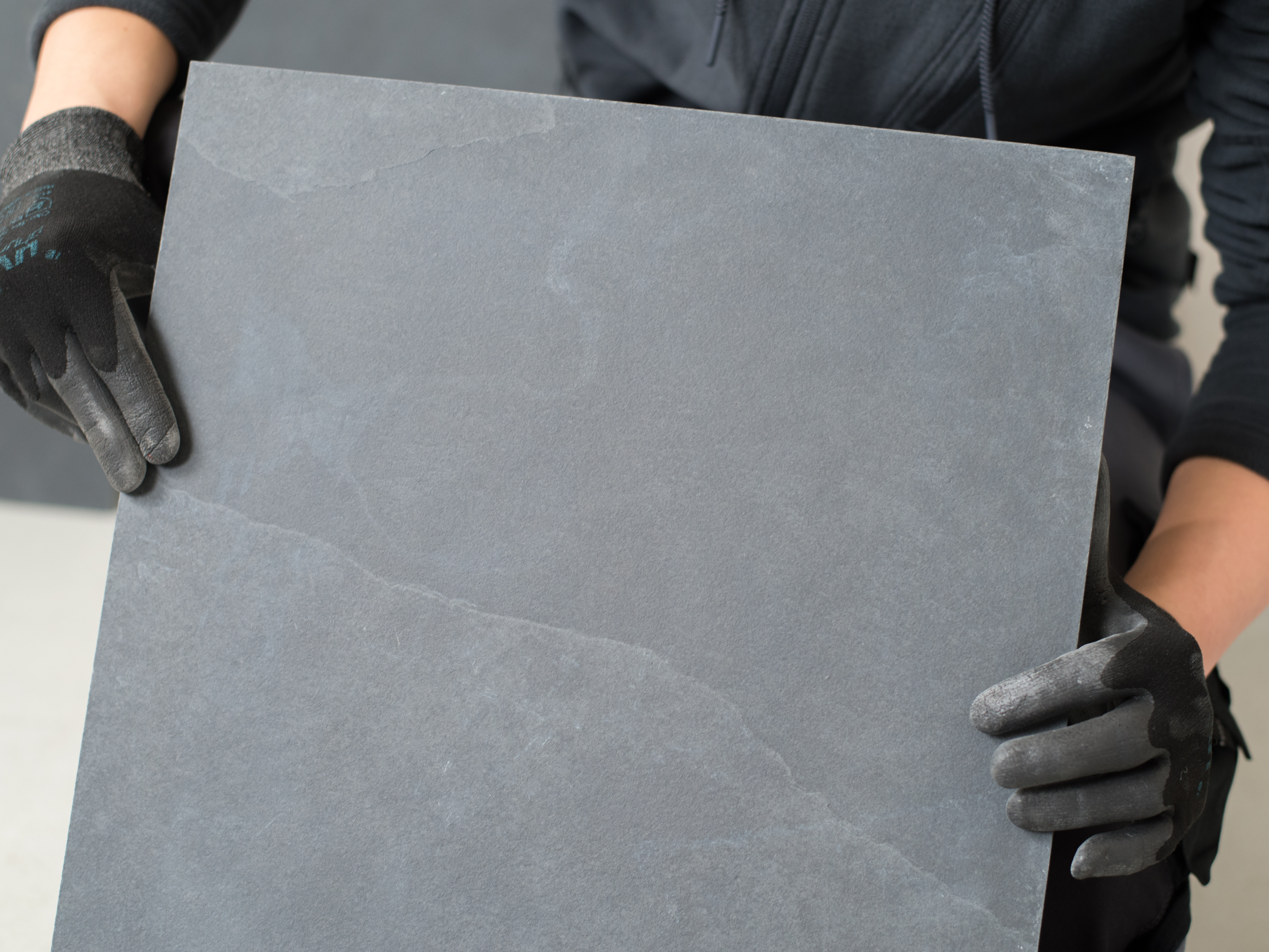 Fliesenleger hält eine Schieferfliese in die Kamera