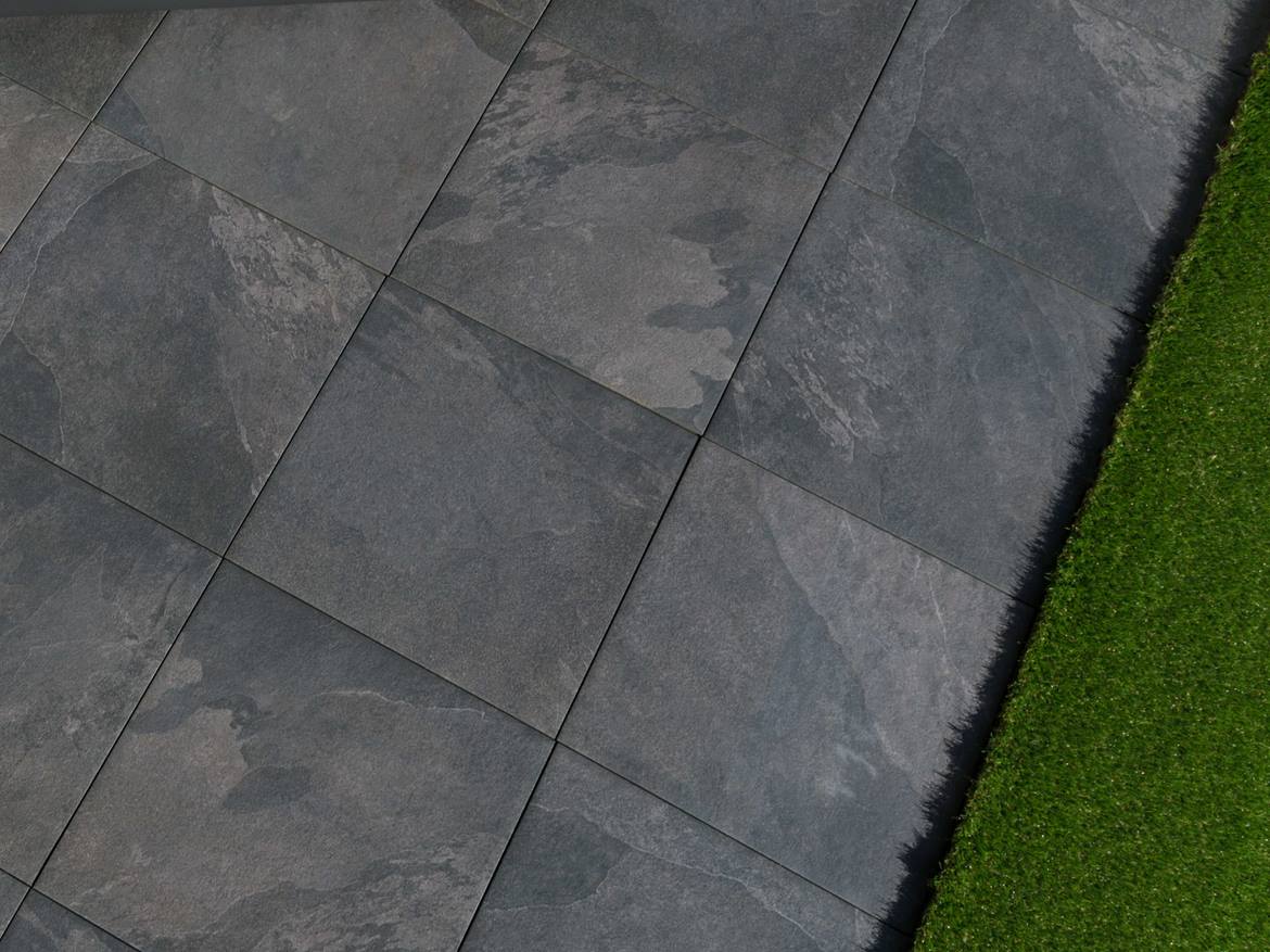Blick von oben auf Schieferoptik-Terrassenplatten im Kreuzverband und Rasenanschnitt