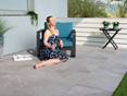 Ideal für Sonnenbäder auf der Terrasse! Frau sitzt auf sonniger Terrasse mit Schieferoptikplatten Alpine Grey