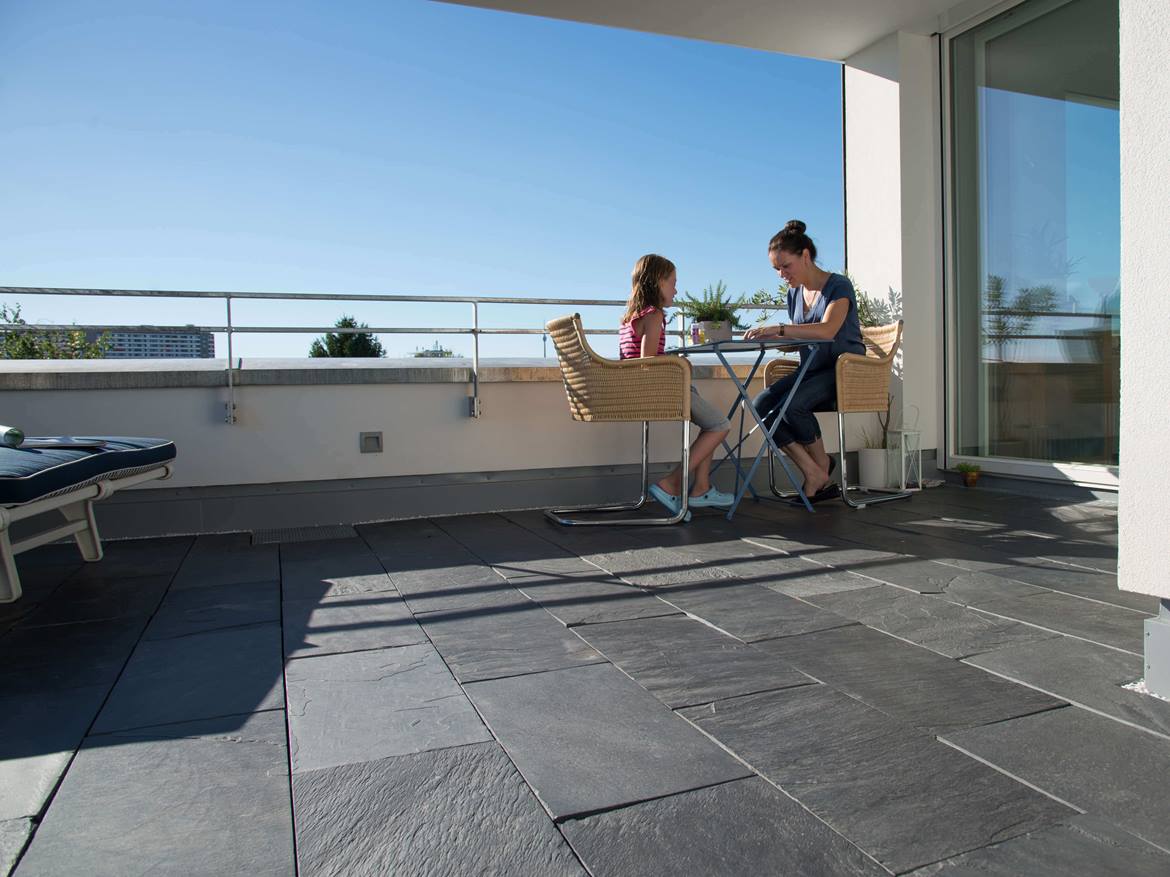 Frau und Kind sitzen an einem Tisch auf der Dachterrasse mit Naturschiefer