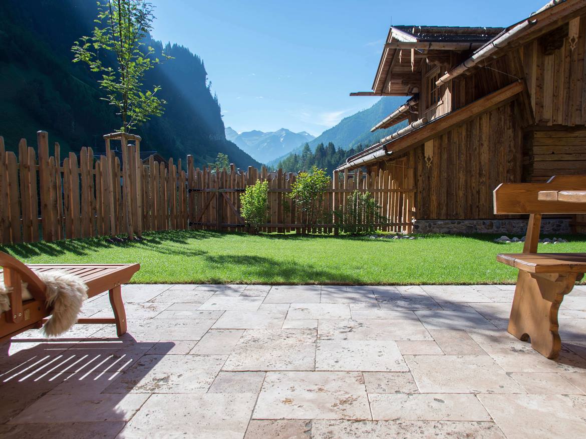 Ausblick vom Chalet, Travertinplatten auf dem Terrassenboden, Holzliegestühle im Bildrand