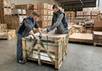 Zwei Lagermitarbeiter packen Fliesen in eine Kiste